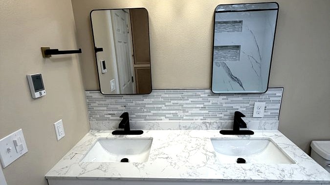 Double vanity bathroom renovation with marble countertop and modern lighting